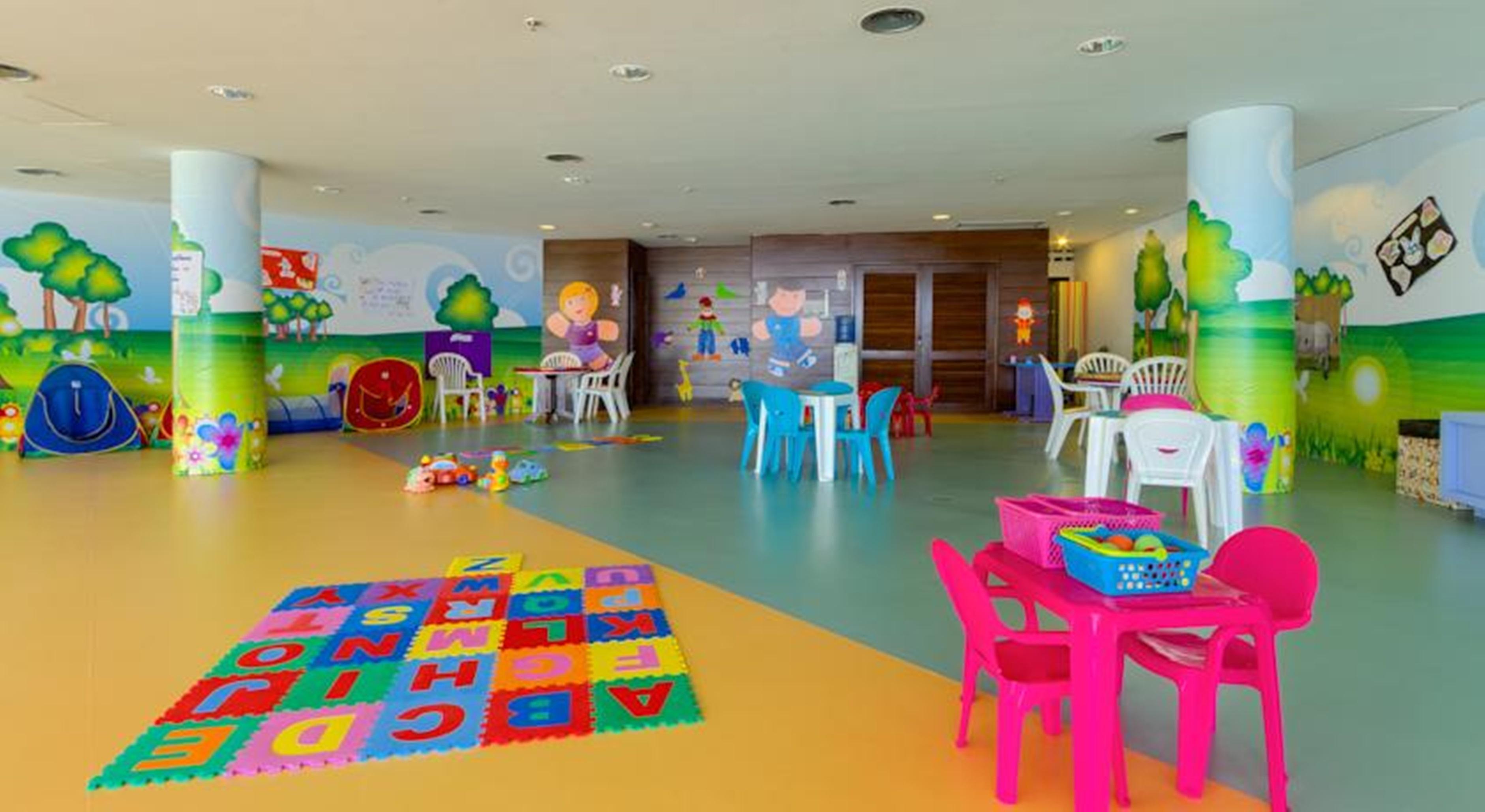 فندق رويال توليب برازيليا ألفورادا المظهر الخارجي الصورة The photo shows a colorful and spacious children's playroom. The floor is divided into sections with different colors, and there is a large play mat featuring letters and numbers. 

In the room, there are several small, lightweight tables and chairs 